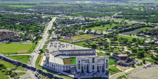 Aerial view of a large stadium surrounded by roads, buildings, and green fields near Village Green Apartments.