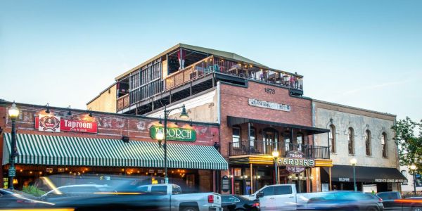 Street view of a bustling historical building with shops and cars in motion at dusk near Village Green Apartments.